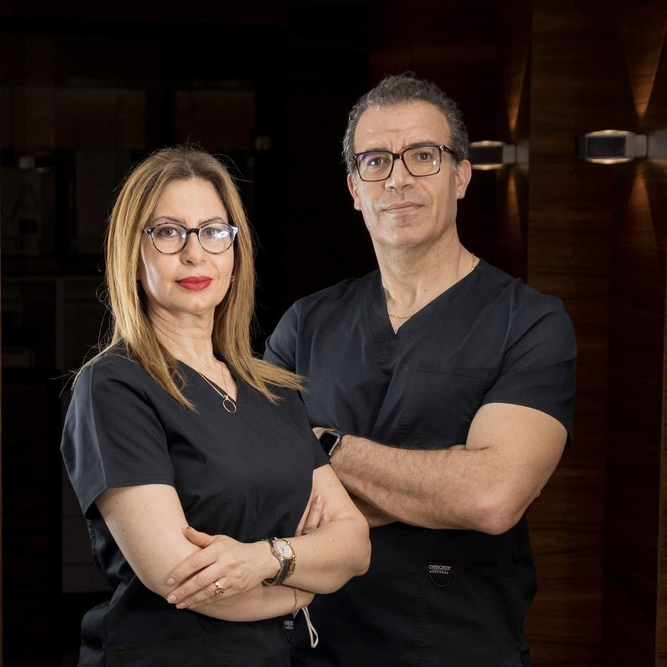 Le Dr et la Dre Frigui, en tenue de praticien, bras croisés dans le cabinet